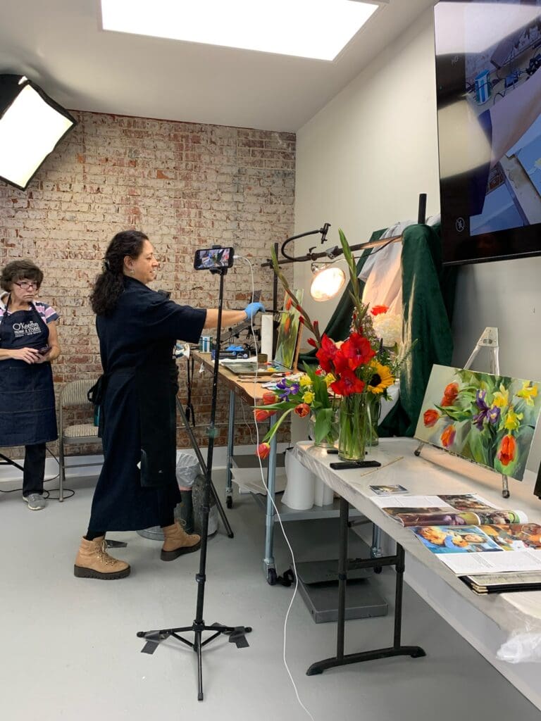 A woman is filming an art show in the studio.