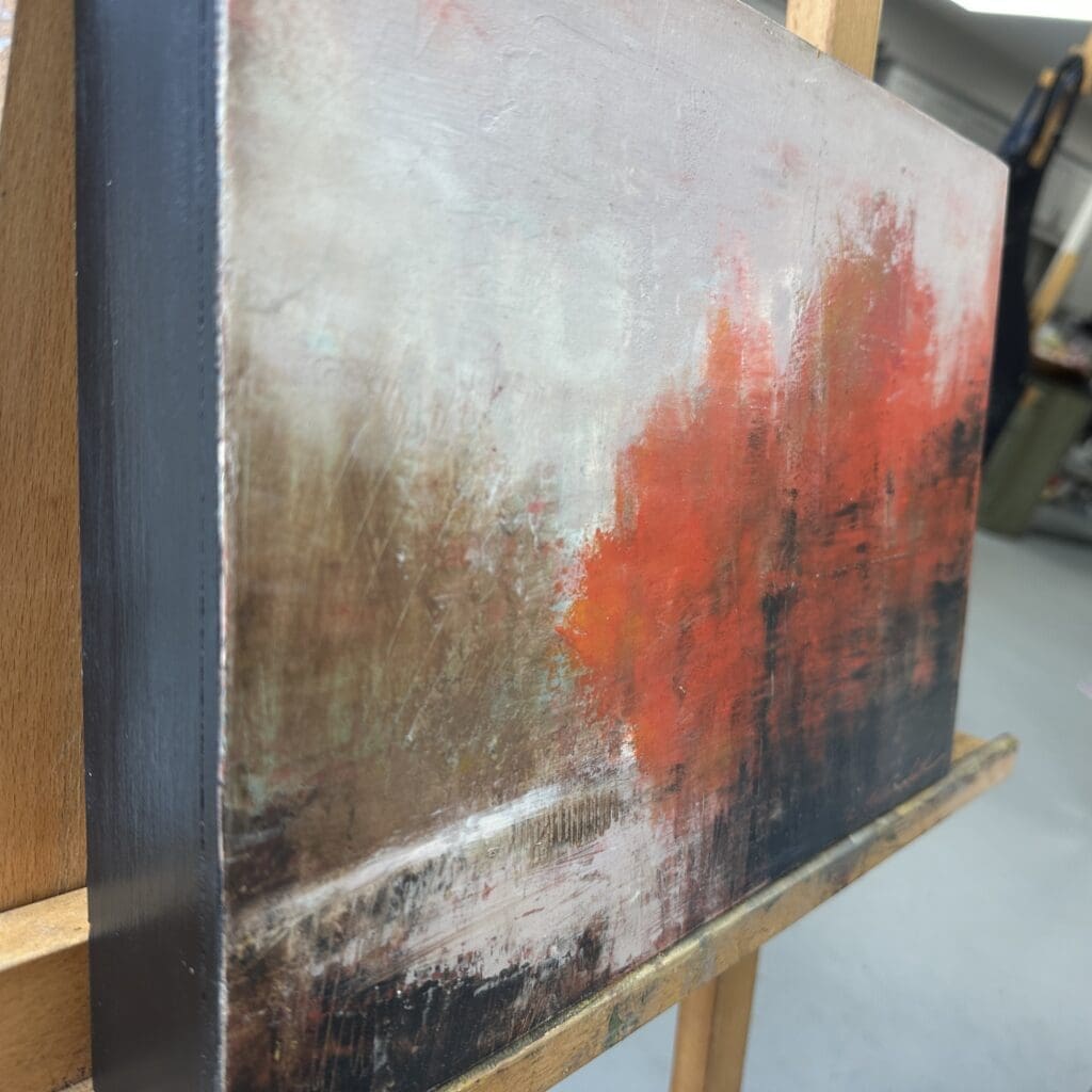 Landscape painting with red trees on easel.